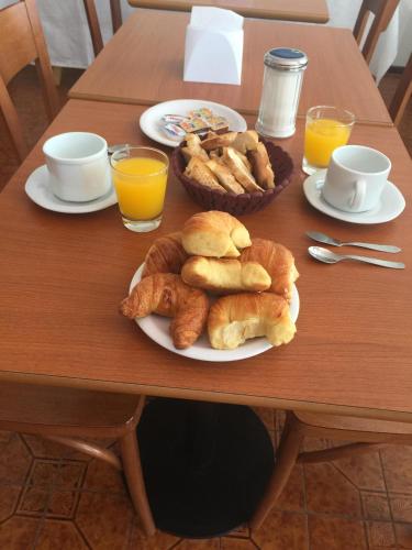 a table with plates of pastries and cups of orange juice at Hotel Davinci in San Bernardo