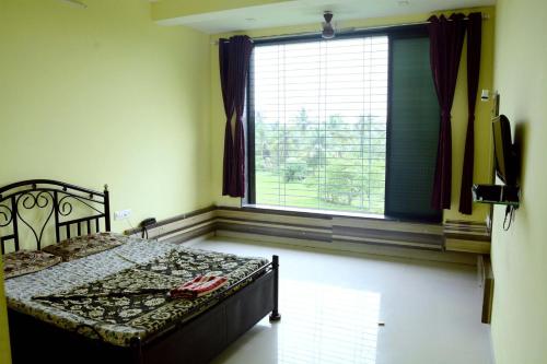a bedroom with a bed and a large window at Shreyas Guest house - Tatkare Villa in Kashid