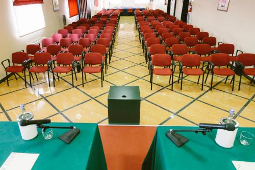 a lecture hall with red chairs and a table with a laptop at Hotel Residence Federiciano in Valenzano