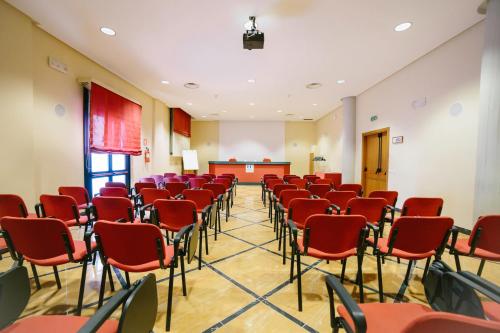 a conference room with red chairs and a podium at Hotel Residence Federiciano in Valenzano