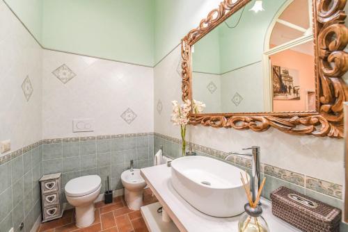 a bathroom with a sink and a toilet and a mirror at Micheli Suite Anfiteatro Square in Lucca