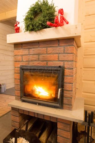 a brick fireplace with a fire in it at Domki pod Kuźnią in Falsztyn