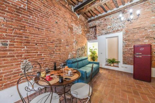 a living room with a brick wall and a table and chairs at Micheli Suite Anfiteatro Square in Lucca