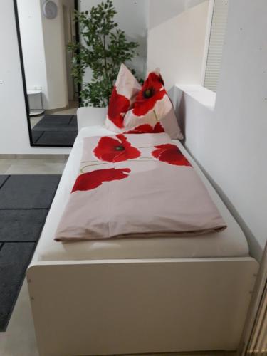 Una cama blanca con flores rojas. en Ferienwohnung Kamot en Steindorf am Ossiacher See