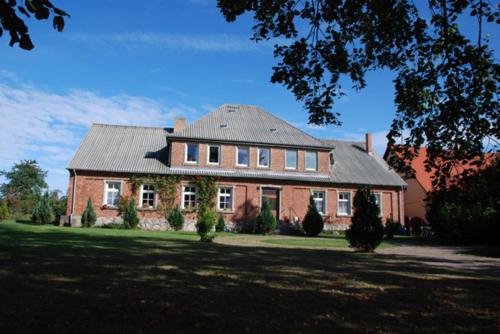 duży ceglany dom z szarym dachem w obiekcie Ferienwohnungen im Gutshaus Gnies w mieście Gnies