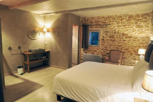サリアンにあるLe Mas Terre Des Anges Giteの白いベッドと石の壁が備わるベッドルーム1室