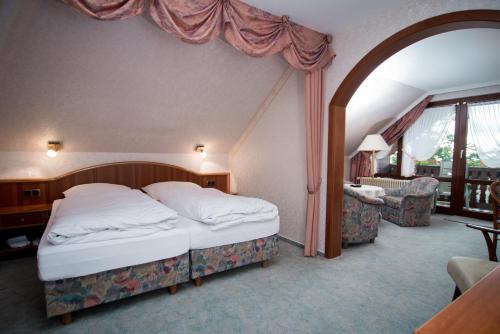 a bedroom with a large bed and a living room at Hotel Sonnenhof in Bad Sachsa