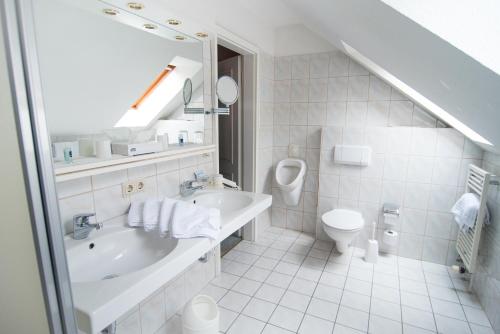 a white bathroom with a sink and a toilet at Hotel Sonnenhof in Bad Sachsa