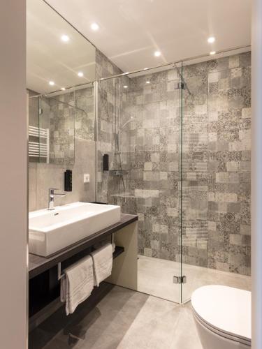 a bathroom with a sink and a glass shower at DECK 8 DESIGNHOTEL.SOEST in Soest