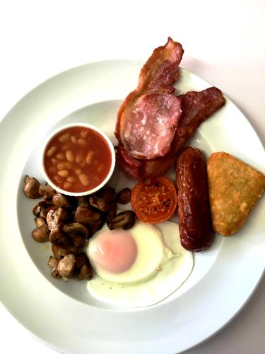 a plate of breakfast food with eggs bacon beans and toast at Penny Farthing Hotel & Cottages in Lyndhurst