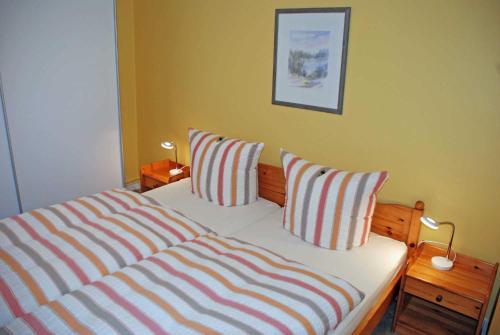 a bedroom with a bed with two striped pillows at Ferienappartements unterm Reetdach in Sandort