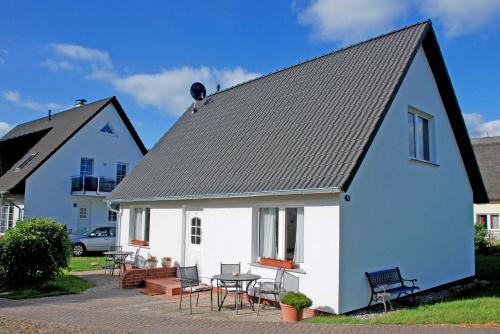 een wit huis met een zwart dak en een patio bij Ferienwohnungen im Haus am Deich in Middelhagen