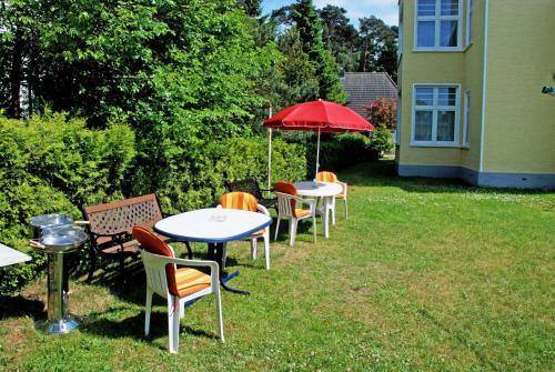 a group of tables and chairs with a red umbrella at Villa Waldblick in Baabe in Baabe