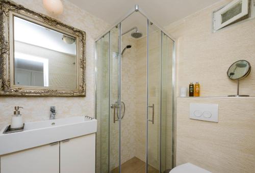 a bathroom with a shower and a sink and a mirror at Leona Apartments in Dubrovnik