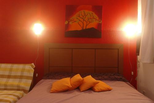 a bedroom with red walls and a bed with orange pillows at Apartamento Casa da Praia in Cabo Frio