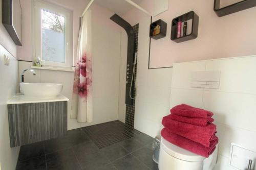 ザスニッツにあるFerienappartement Feuersteinのバスルーム(洗面台付)、トイレ(赤いタオル付)