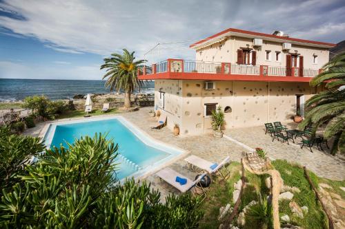 a house with a swimming pool next to the ocean at Pericles Beach Villa in Kissamos