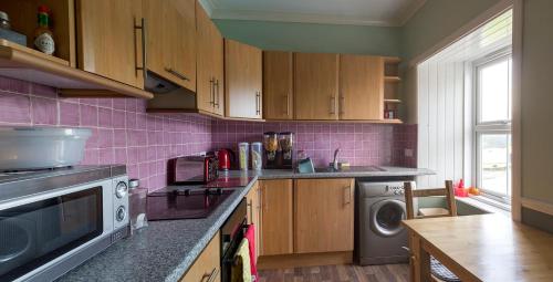 a kitchen with pink tiles on the wall at Bannockburn Inn in Helmsdale