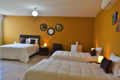 Habitación de hotel con 2 camas y paredes amarillas en Kajaca Suite Hotel, en Huacho