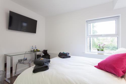 a bedroom with a white bed with pink pillows and a television at The Orlando in Cambridge