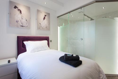 a bedroom with a white bed and a glass shower at The Orlando in Cambridge