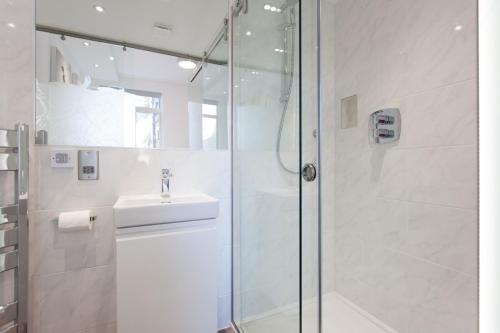 a white bathroom with a shower and a sink at The Orlando in Cambridge