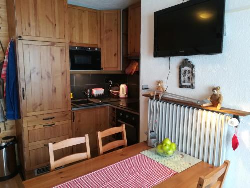 a kitchen with a table and a television on the wall at Romantic Chalet-Style Flat with Mountain View in Torgon