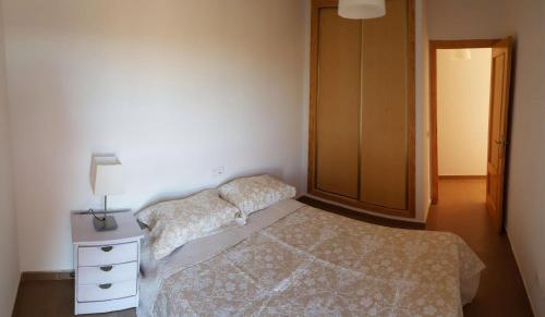 um quarto com 2 camas e uma cómoda com um candeeiro em Apartamento em Los Urrutias