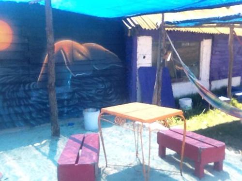 a playground with a swing and a table and benches at cabopolonioalojamiento in Cabo Polonio