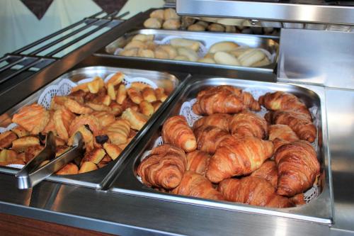 a buffet filled with trays of croissants and other pastries at Eira do Serrado - Hotel & Spa in Curral das Freiras