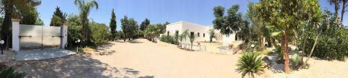 a large yard with a white building and trees at Casa Giada B&B in Gallipoli