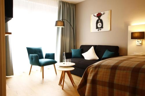 een slaapkamer met een bed, een bank en een tafel bij Gästezimmer Kamino in Häusern