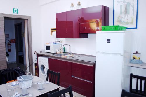 ローマにあるIn vacanza da Saraのキッチン(赤いキャビネット、白い冷蔵庫付)