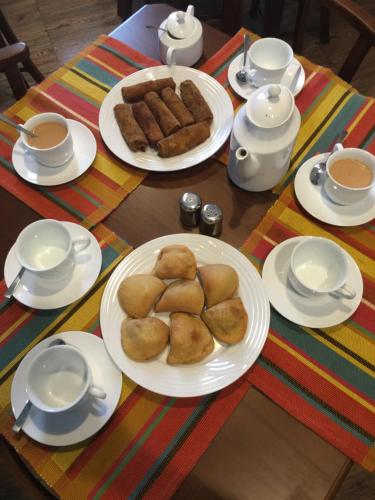 una mesa con platos de comida y tazas de café en Villa 92 City Stay en Kandy