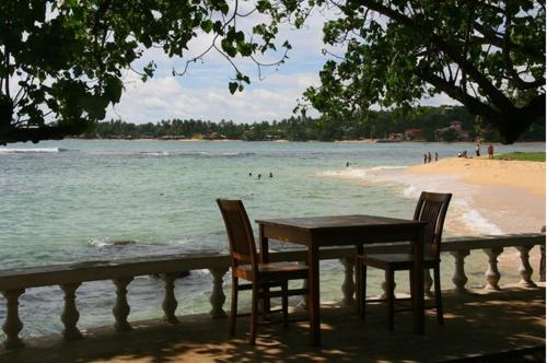a table and chairs sitting next to a beach at Sun N Sea Hotel in Unawatuna