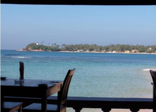 a table with chairs and a view of the ocean at Sun N Sea Hotel in Unawatuna