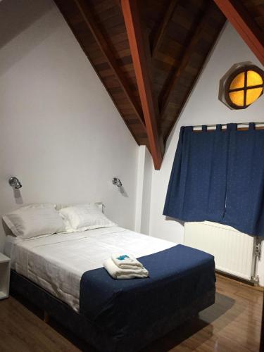a bedroom with a bed with a blue blanket and a window at Hosteria Kupanaka in Ushuaia