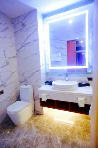 a bathroom with a sink and a toilet and a mirror at Bella Vita Hotel in Long Hai