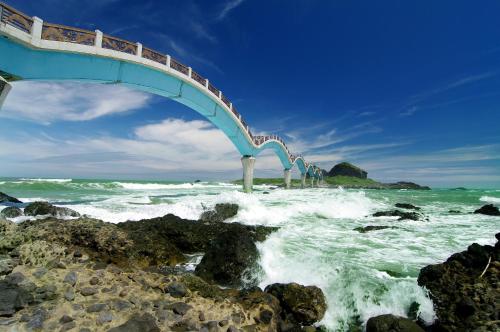 a bridge over a body of water with waves at Gui Ren Sha Cheng Guest House in Chenggong