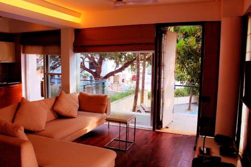 a living room with a couch and a sliding glass door at Luxurious 2BHK for Ultimate Holiday Experience in Goa - 2 in Candolim