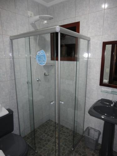 a shower with a glass door next to a sink at Pousada Torre Del Mar in Ubatuba