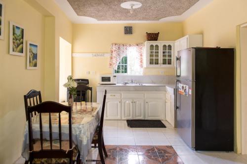 a kitchen with a table and a refrigerator at Relax in Sunny Montego Bay, Jamaica in Montego Bay