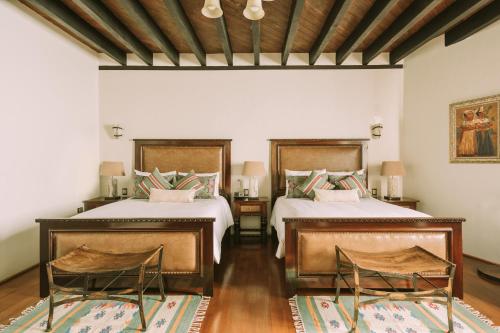 a bedroom with two beds and two chairs in it at Casona de los Sapos Hotel Boutique in Puebla