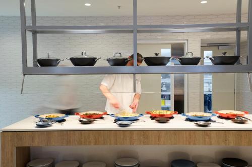 a chef in a kitchen preparing food in bowls at Pullman Melbourne On the Park in Melbourne