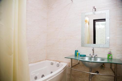 a bathroom with a sink and a tub and a mirror at Academic Apartments in Almaty