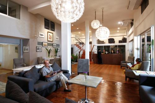 ein Mann, der auf einer Couch in einem Wohnzimmer sitzt in der Unterkunft Ratchadamnoen Residence in Bangkok