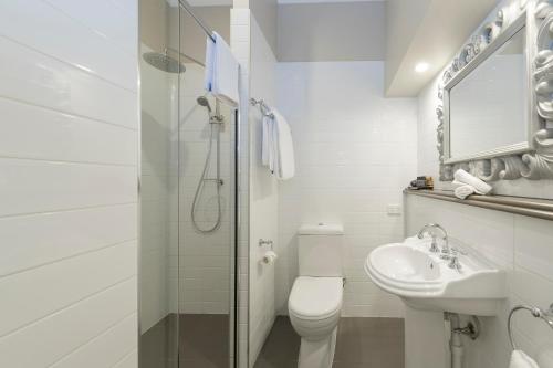 a white bathroom with a toilet and a sink at Grand Mercure Basildene Manor in Margaret River Town