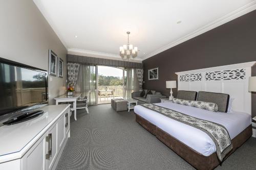 a bedroom with a king sized bed and a bathroom at Grand Mercure Basildene Manor in Margaret River Town