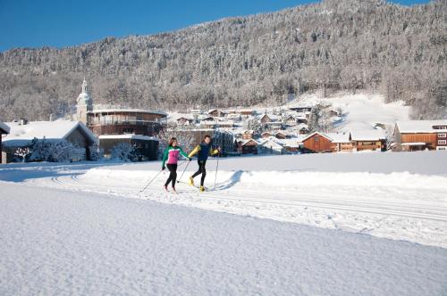 two people are cross country skiing in the snow at Gästehaus Meusburger in Bezau