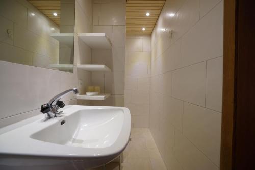 a white bathroom with a sink and a mirror at Gästehaus Meusburger in Bezau